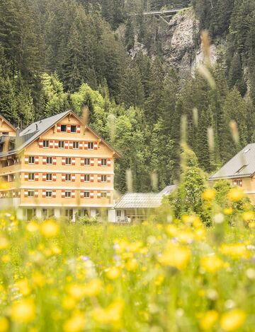 Au&szlig;enansicht des Berghaus Schr&ouml;cken, eine bunte Wiese schm&uuml;ckt das Areal rund um die Anlage